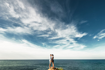 Couple in love at the top of the mountain. Guy and girl on the beach. Lonely couple on a cliff by the sea. Man and woman hugging on a rock. Man and woman kissing. The pair on the island. Lover