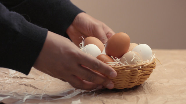man takes eggs from the basket and put it to the baxoes. Small farmm worker