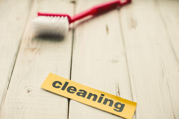 Cleaning house or office concept. Red cleaning brush and Cleaning inscription on a white wooden background. Top view, closeup