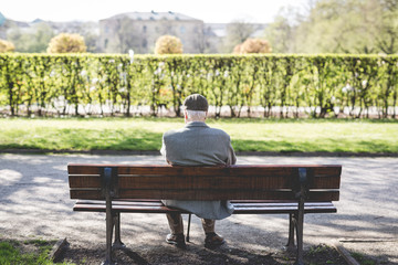 Naklejka na ściany i meble old man sitting on a bench in the park