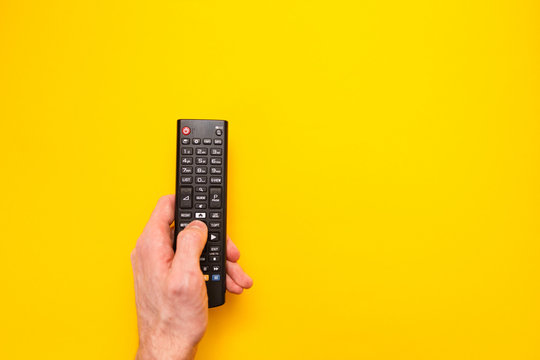 Television remote control in the hand isolated on yellow background