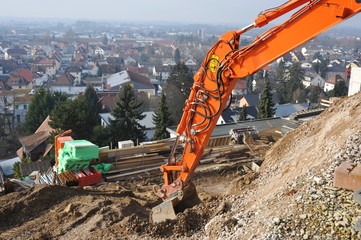 Baggerausleger zur Herstellung eines Planums an einer Baustelle am Hang über der Stadt