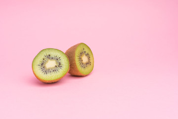 The concept of healthy eating. Half-cut kiwi on a pastel pink background.