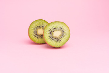 The concept of healthy eating. Half-cut kiwi on a pastel pink background.