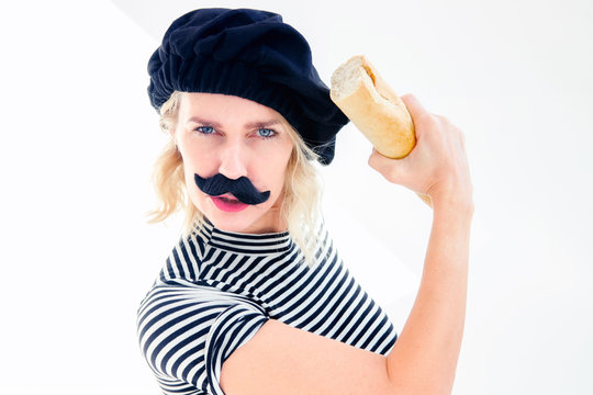 woman dressed as french man with mustache and beret holding  baguette