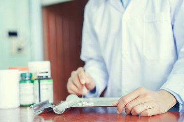 close up on pharmacy doctor trying to manage medicine pills or patient customer on counter desk , healthcare concept