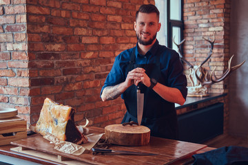 Professional butcher holds a knife standing with raw smoked meat