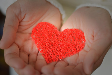 Decorative red heart in female hands. Valentine's Day. Love and romance. Medicine, health and care.