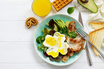 English breakfast - fried egg, fried bacon, spinach, arugula, avocado, toast and orange juice. Top view with copy space.
