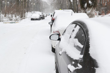 Cars under the snow. Snowfall in the city