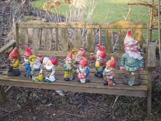 Deko - bunte Gartenzwerge stehen auf Holzbank