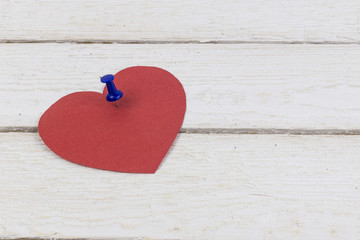 Empty heart shaped paper sticker pinned on wood. Copy space