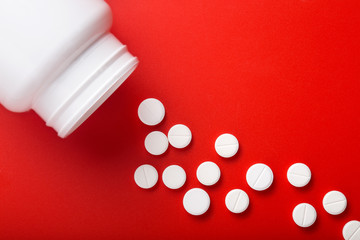 Medical pills spilling out of bottle. On red background. Top view  Medicine concept