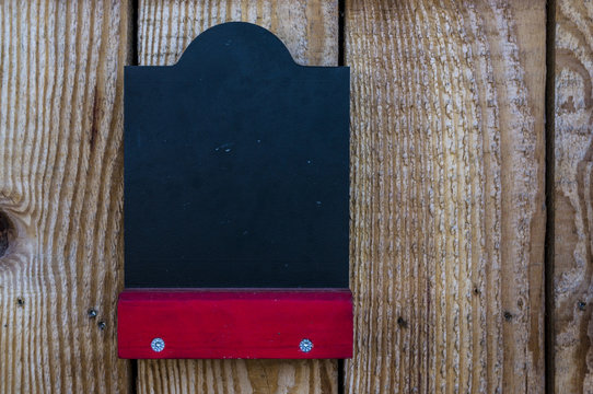 leere Kreidetafel an einem Verkaufsstand aus Holz mit roter Ablage zum frei beschriften, empty chalk board on a wooden sales stand with red shelf for free labeling