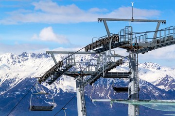 Fototapeta premium Chairlift in the Italian Alps. Chair lift in snowy mountains at nice sunny day.