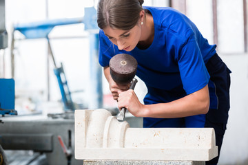 Bildhauerin meißelt eine Säule aus Stein in ihrer Werkstatt