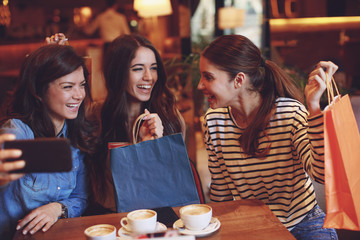 Three women making selfie after shopping in a cafe