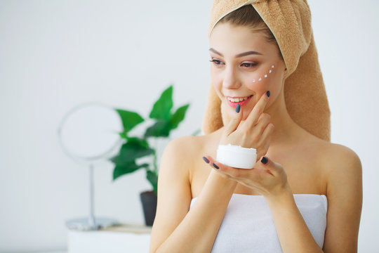 Portrait of beautiful woman applying cream on face