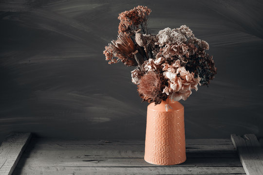 Fototapeta Still life image of dried flowers in rustic vase against weathered wooden background