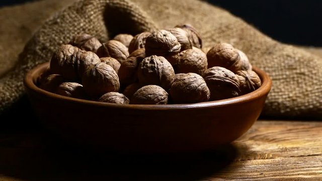 Walnut in the shell in a plate on the table. Strew the shell of nuts. Kernels of nuts.