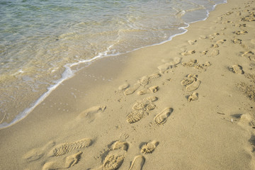 Fototapeta na wymiar Mediterranean scene, shore of the Mediterranean Sea with barefoot footprints of people in summer