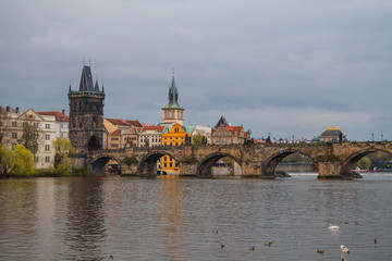 Fototapeta na wymiar Charles bridge in gloomy day, Prague, Czech Republic. Water front of old museums.