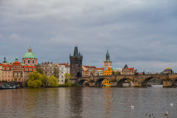 Naklejka premium Charles bridge in gloomy day, Prague, Czech Republic. Water front of old museums.