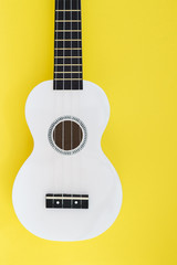 White ukulele on a yellow background. Flat lay Musical concept