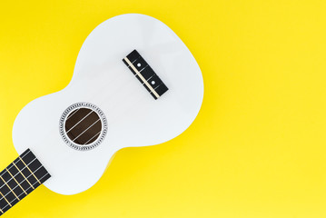 White ukulele on a yellow background. Flat lay Musical concept. Place for text.