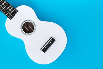 White Hawaiian guitar, ukulele on a blue background. Musical concept. Flat Lay Template. Place for text