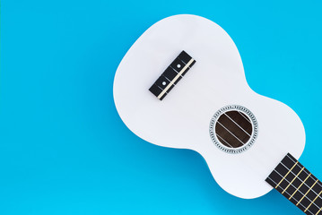 White ukulele on a blue background. Musical concept. Flat Lay Ukulel. Place for text