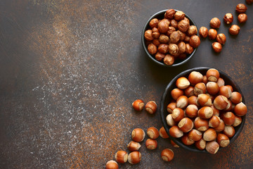 Peeled and unpeeled hazelnuts in a bowl.Top view with copy space.