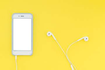 Smartphone with a white screen with headphones on a yellow background. Top view. Flat lay.