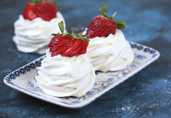 Three homemade mini cakes with meringue (pavlova) and cream cheese with strawberries. Selective focus.