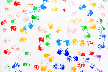 Color prints of children's hands on a white canvas. Imprint of the children's palm on the canvas. Prints of colored hands. Many children's colorful hands.