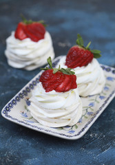 Three homemade mini cakes with meringue (pavlova) and cream cheese with strawberries. Selective focus.