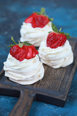Three homemade mini cakes with meringue (pavlova) and cream cheese with strawberries. Selective focus.