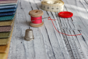 Multicolored fabric samples. A button with a needle and a thread on the tissues with space for text.