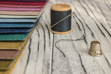 Multicolored fabric samples. A button with a needle and a thread on the tissues with space for text.