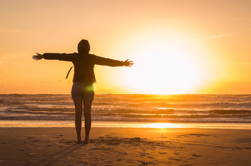 Fototapeta premium Woman looking at the horizon, beach at sunset