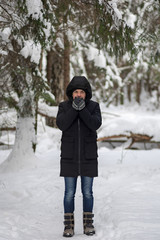 Fototapeta na wymiar Man walk in snowy winter forest and warms your hands with your breath