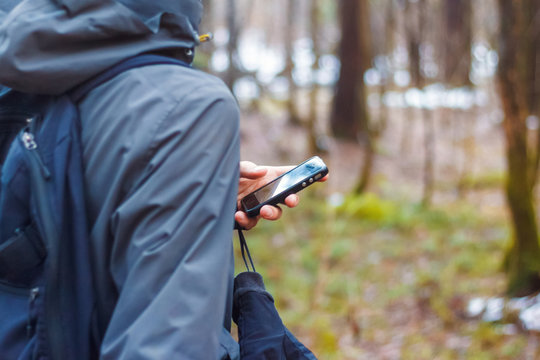 Man hand holding smart phone device in the forest and looks at the map