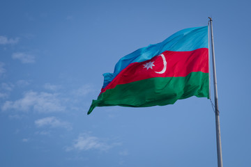The national flag of Azerbaijan on the background of blue sky . Azerbaijan flag waving in the wind against cloudy sky