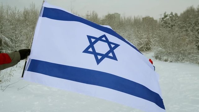 Israel flag waving in the wind, highly detailed fabric texture. Israel flag on ski slope winter day.