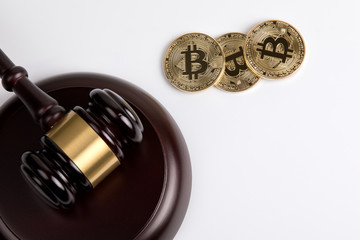 crypto currency, golden bitcoin with a wooden judges gavel on white background.