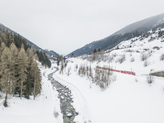 Fototapeta na wymiar Aerial view of river in snow covered landscape in swiss mountains