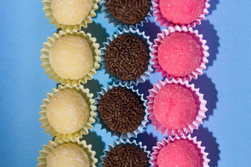 Brigadeiro Beijinho and Bicho de Pe: sweets from Brazil. Child birthday party. Overhead of candy ball on blue table.