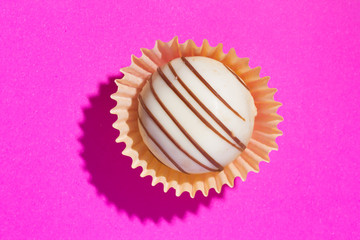 Homemade white chocolate truffle. Flat design of candy ball over pink color.