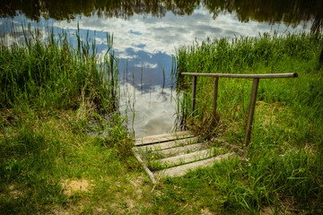 Vakulenchuk, Zhytomyr region., Ukraine. A beautiful forest lake with a reflection of the sky-high sky. Beautiful landscape. Lake in a green forest. Wooden Stairs in the Forest Lake.