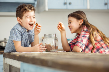 Entertaining. Adorable exuberant little dark-haired brother and sister laughing and eating cookies...